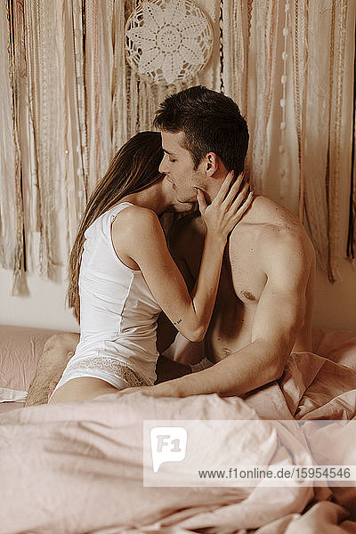 Intimes junges Paar umarmt und küsst sich im Bett