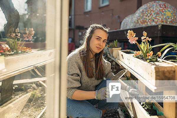 Porträt einer jungen Frau  die bei Sonnenschein im Garten arbeitet