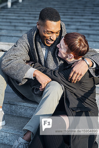 Glückliches junges Paar umarmt sich auf einer Treppe in der Stadt