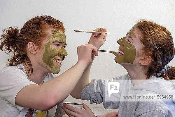 Brother and sister applying facial mask having fun