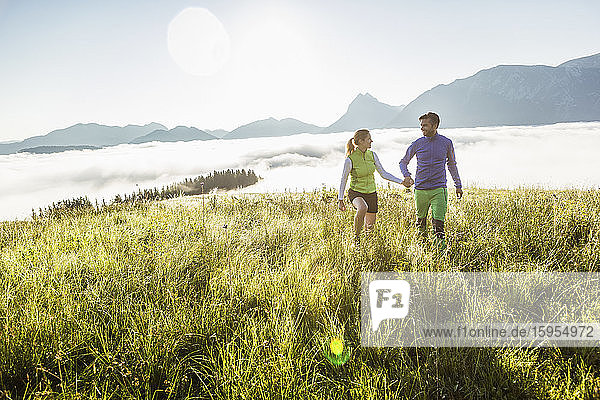 Couple hiking on a meadow in the mountains at sunrise  Achenkirch  Austria