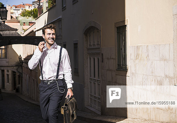 Lächelnder junger Mann mit Ohrstöpseln in der Altstadt  Lissabon  Portugal