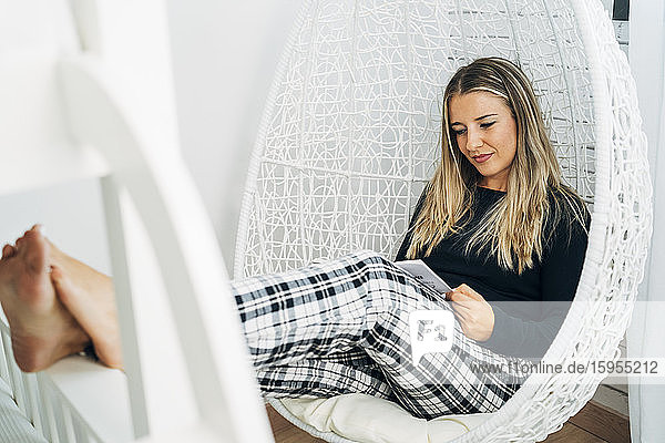 Porträt einer Frau  die zu Hause auf einem Schaukelstuhl sitzt und ein Buch liest