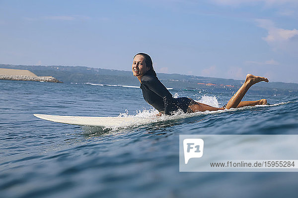 Glückliche Frau liegt auf einem Surfbrett im Meer  Bali  Indonesien