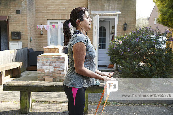 Side view of woman exercising with resistance band