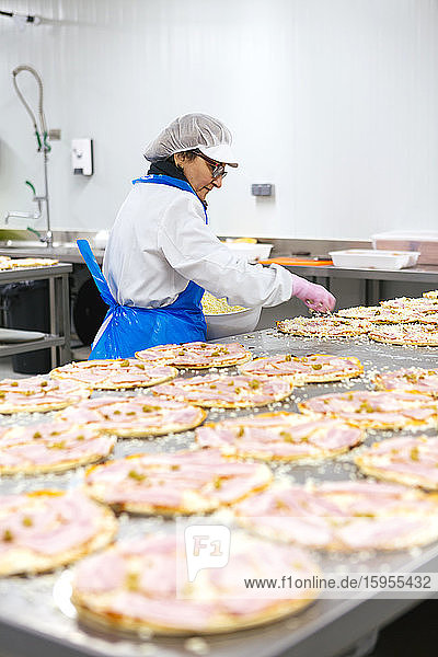 Woman preparing pizzas in pizza company