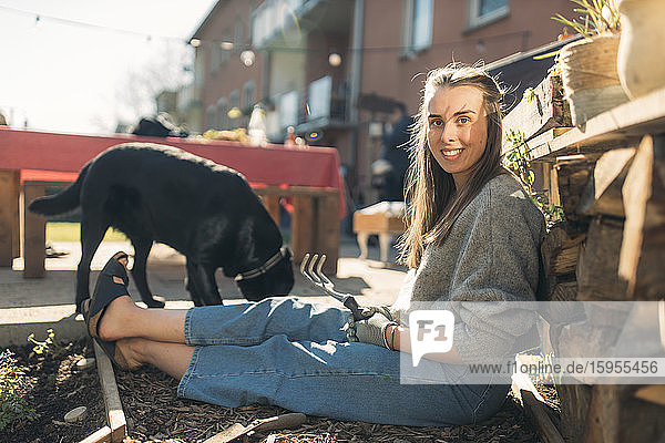 Glückliche junge Frau mit Hund im Garten