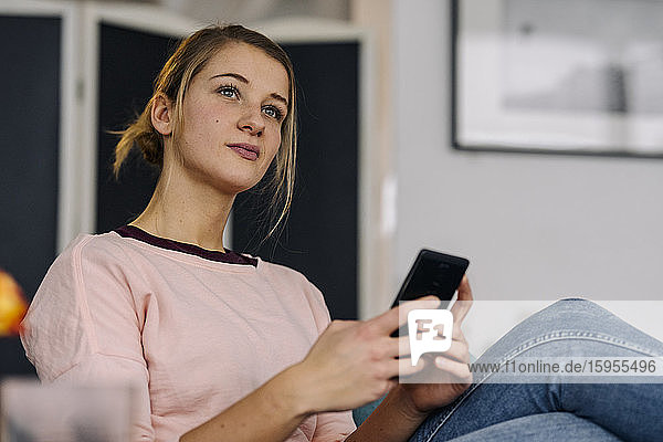 Portrait of relaxed young woman holding smartphone