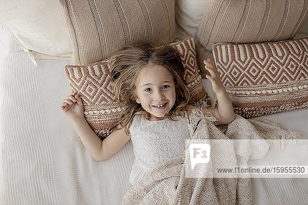 Portrait of happy little girl lying on bed