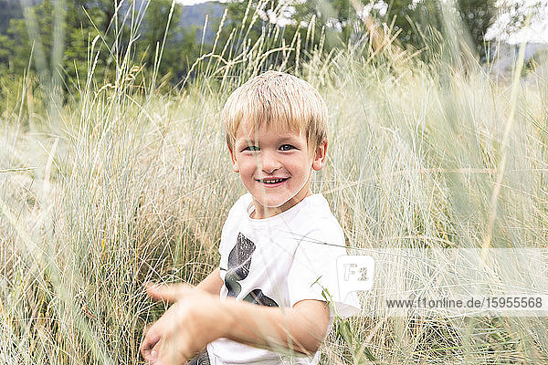 Porträt eines blonden kleinen Jungen im hohen Gras