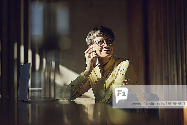 Businesswoman sitting in her sustainable office  talking on the phone