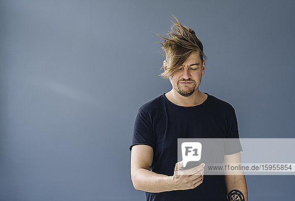 Bärtiger Mann mit zerzaustem Haar mit Smartphone