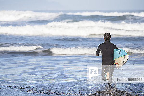 Behinderter Surfer mit Surfbrett am Strand