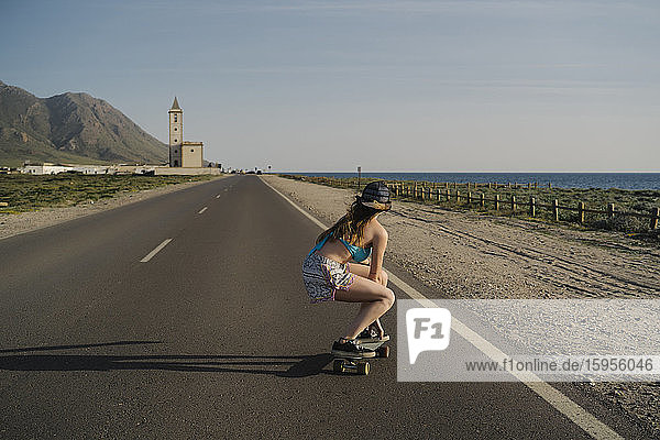 Rückenansicht einer jungen Frau beim Skateboarden auf Asphaltstrasse  Almeria  Spanien