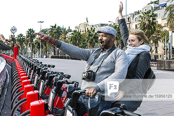 Happy couple at bike share stand in city  Barcelona  Spain