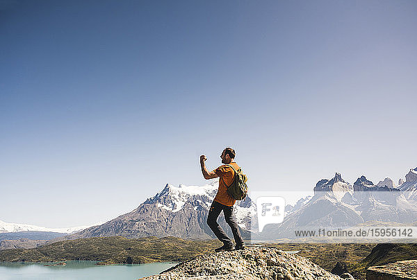 Hiker cheering in mountainscape at Lago Pehoe in Torres del Paine National Park  Patagonia  Chile