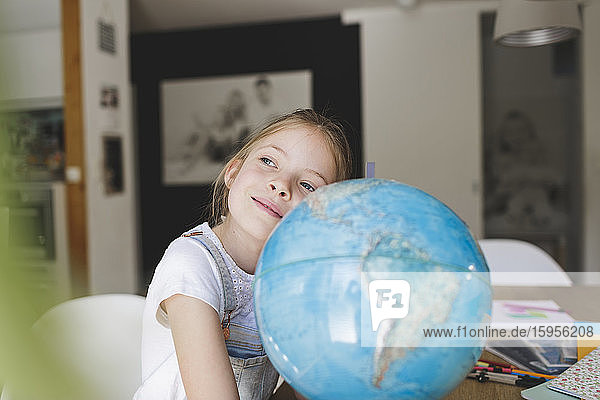 Porträt eines träumenden Mädchens zu Hause  das sich an den Globus lehnt