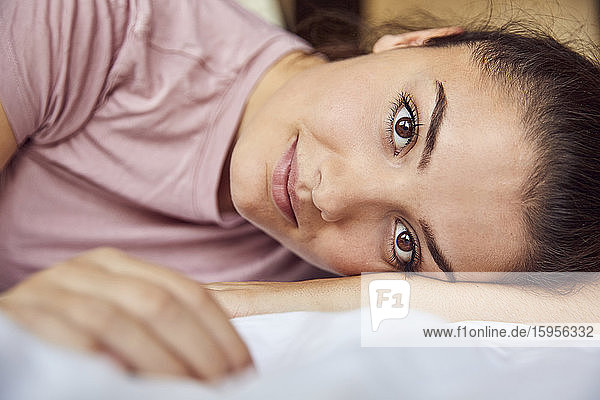Bildnis einer auf dem Bett liegenden jungen Frau mit braunen Augen