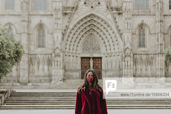 Portrait of woman wearing face mask standing against Barcelona Cathedral during quarantine  Barcelona  Spain