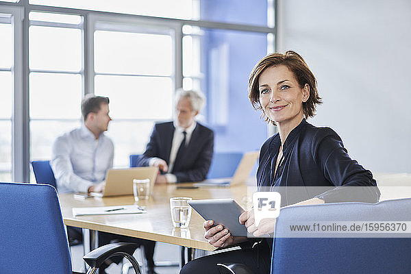 Porträt einer Geschäftsfrau mit Tablett während einer Besprechung im Büro