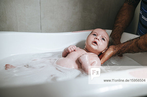 Baby girl bathing  holding by father's hands