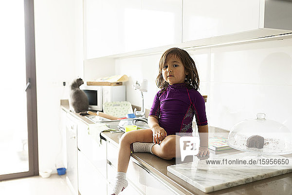 Porträt eines Kleinkindes  das auf der Arbeitsplatte in der Küche sitzt