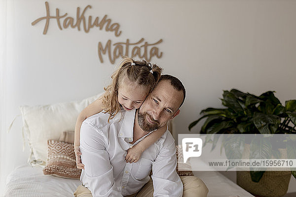 Porträt eines glücklichen Vaters und seiner kleinen Tochter  die zu Hause kuscheln