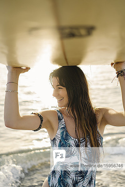 Portrait of smiling young woman with surfboard on the beach  Almeria  Spain