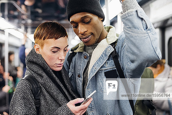 Junges Paar benutzt Smartphone in der U-Bahn
