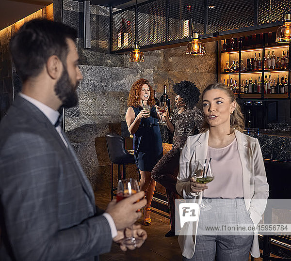 Mann und Frau unterhalten sich mit Cocktails in einer Bar
