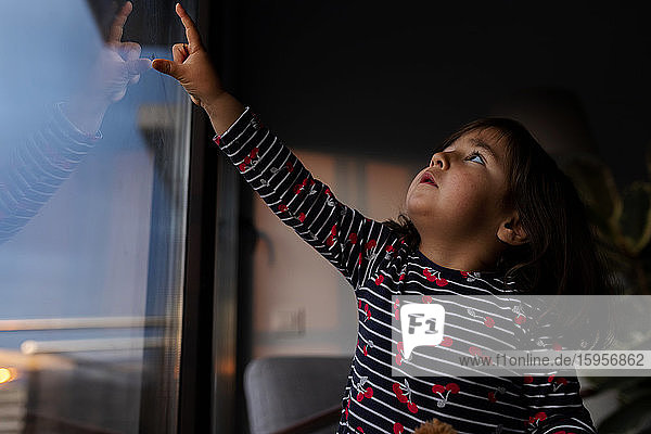 Little girl looking out of window in the evening