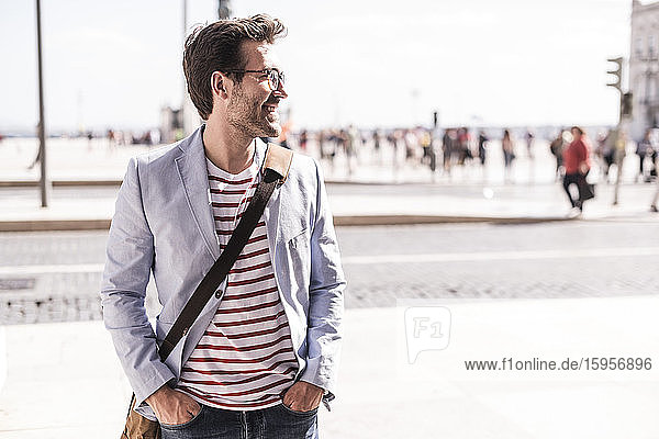 Lächelnder junger Mann in der Stadt mit seitlichem Blick  Lissabon  Portugal