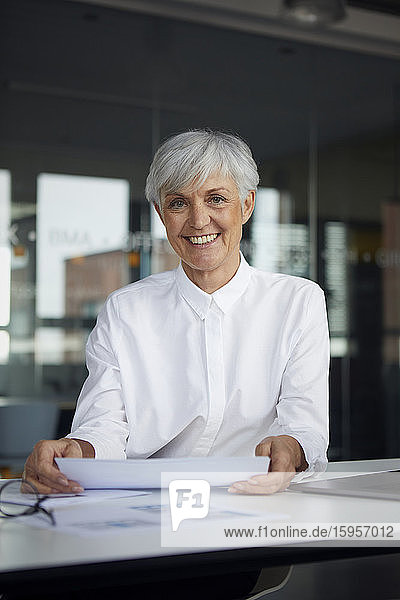 Portrait of smiling senior businesswoman at desk in her office