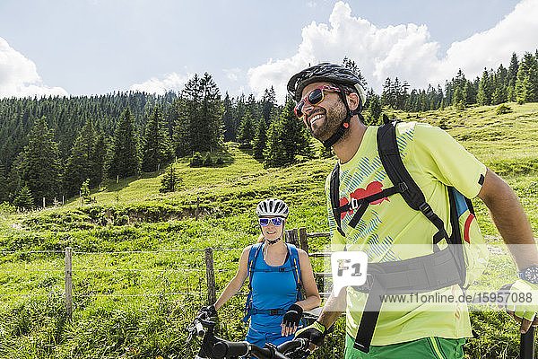 Happy couple with mountain bikes at a meadow in the mountains  Achenkirch  Austria