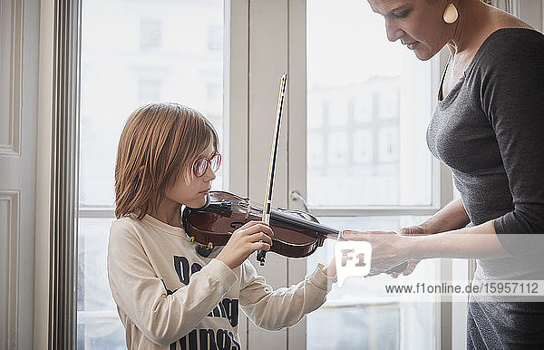 Lehrer unterrichtet einen Jungen  der während einer Unterrichtsstunde Geige spielt