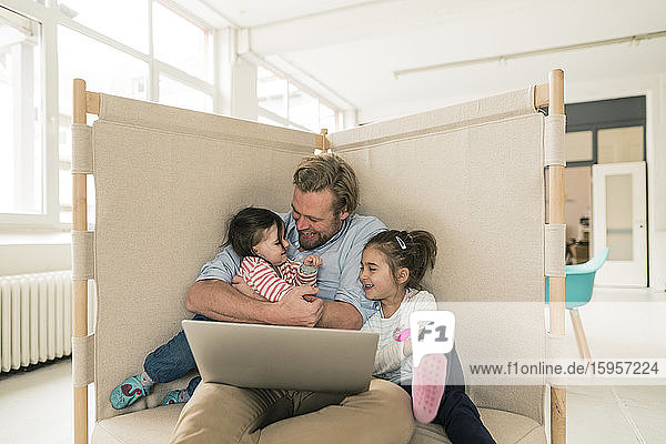 Father playing with two daughters in home office
