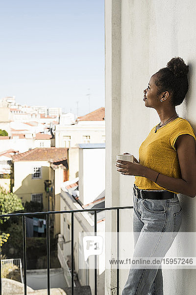 Junge Frau mit Kaffeetasse auf einem Balkon