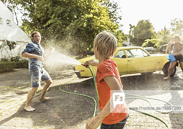 Freunde waschen im Sommer gelben Oldtimer und haben Spaß
