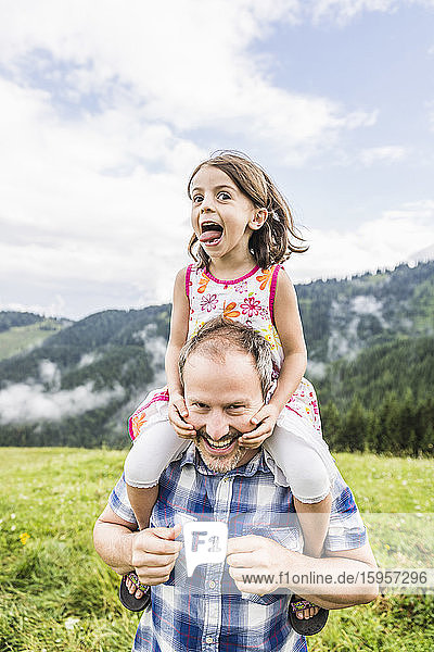 Happy father carrying daughter on shoulders on a meadow in the mountains  Achenkirch  Austria
