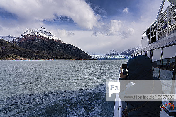 Tourist  der den Gletscher Perito Moreno vom Boot aus fotografiert  El Calafate  Nationalpark Los Glaciares  Patagonien  Argentinien