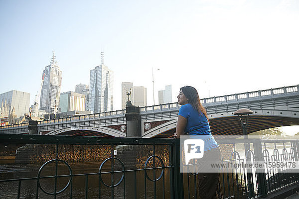 Frau steht an der Promenade des Yarra River  im Hintergrund die Skyline von Melbourne  Australien.