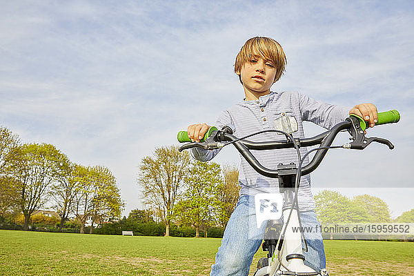 Brünetter Junge fährt mit seinem BMX-Rad in einem Park.