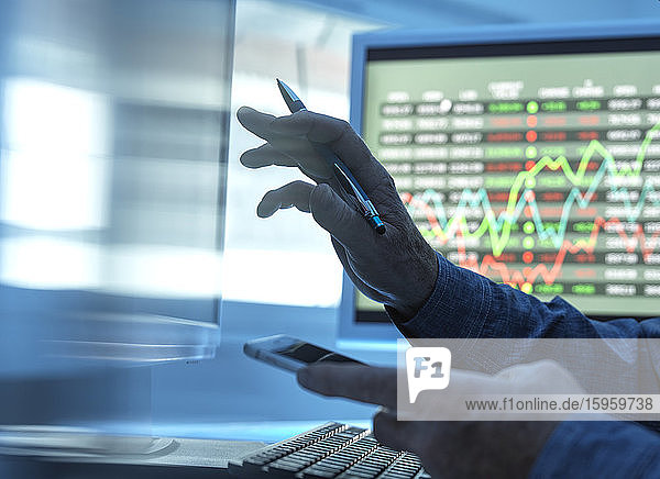 Nahaufnahme eines Börsenhändlers der Aktienkursdaten auf dem Bildschirm analysiert.