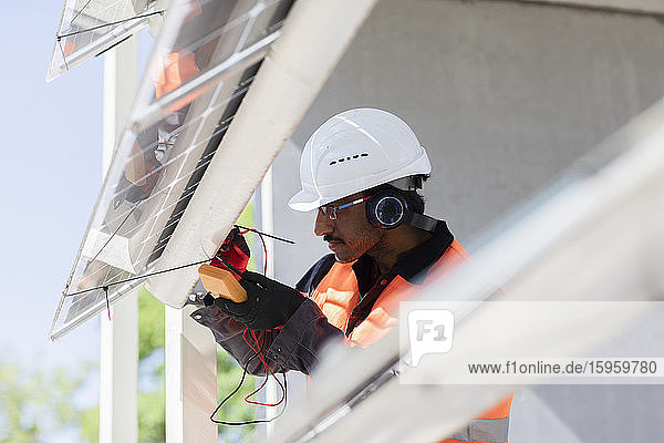 Männlicher Ingenieur mit Schutzhelm und Gehörschutz bei der Arbeit auf der Baustelle.
