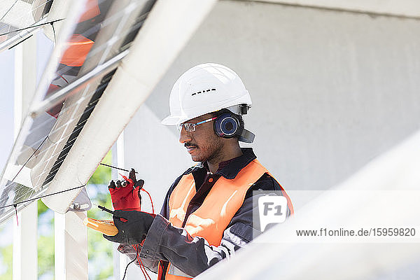 Männlicher Ingenieur mit Schutzhelm und Gehörschutz bei der Arbeit auf der Baustelle.