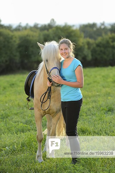 Smiling girl with horse on meadow