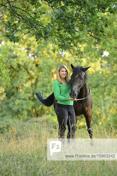 Smiling teenage girl with horse on meadow