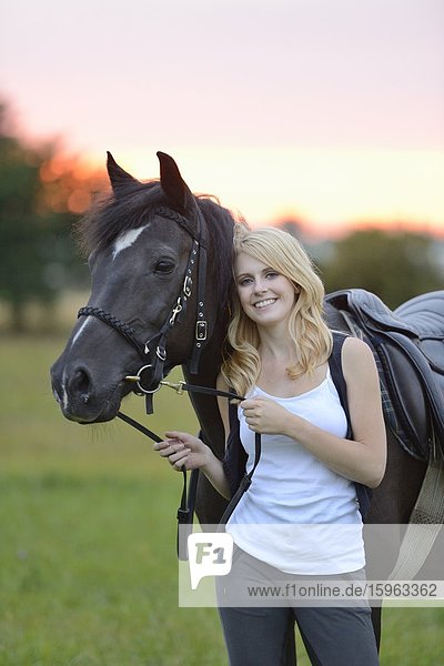 Lächelnde Frau mit Pferd auf einer Wiese