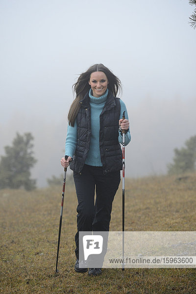Brünette junge Frau macht Nordic Walking
