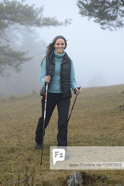 Brünette junge Frau macht Nordic Walking